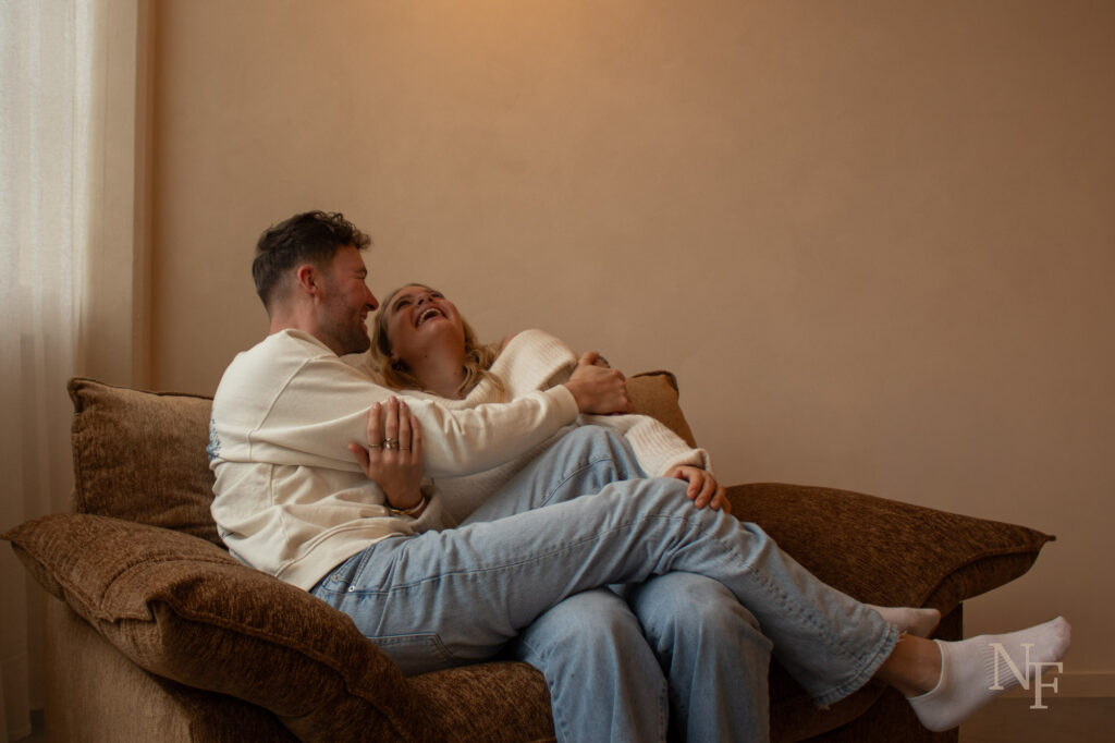 man en vrouw lachend en omhelsend op een bank