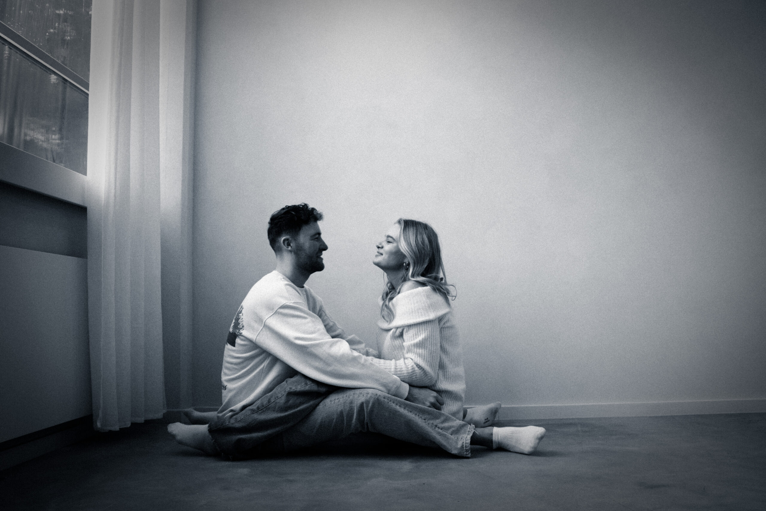 jonge man en vrouw die op de grond zitten en elkaar omhelzen