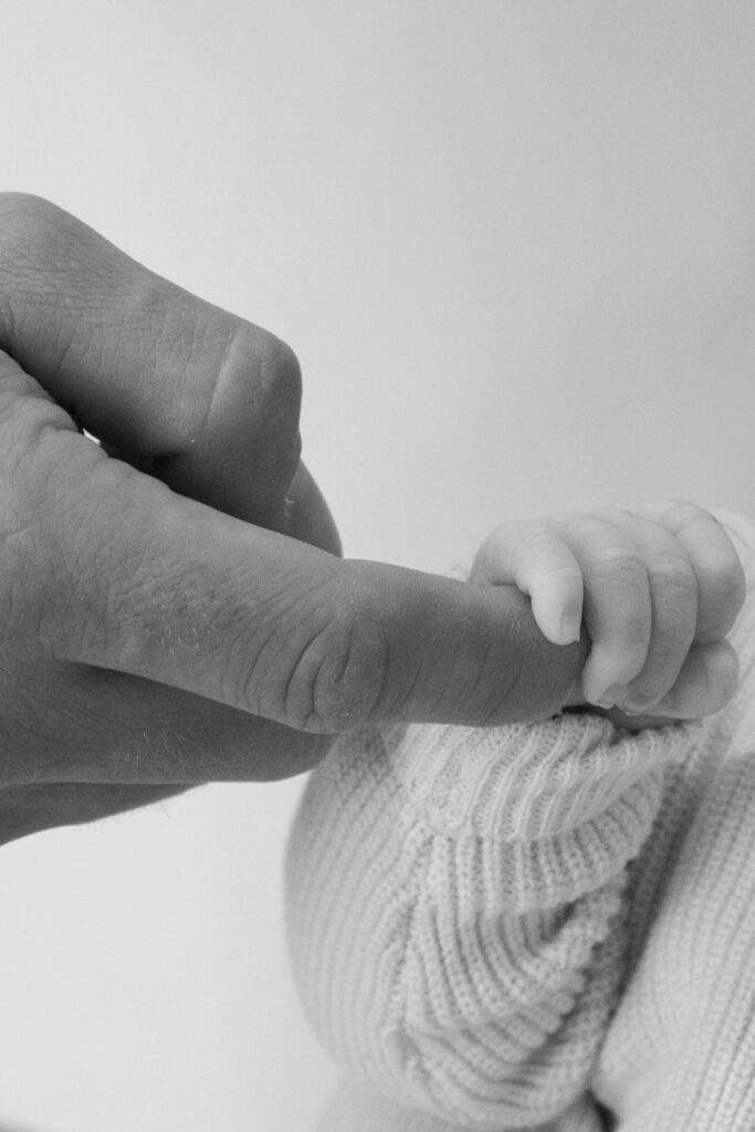 hand van baby om vinger van vader